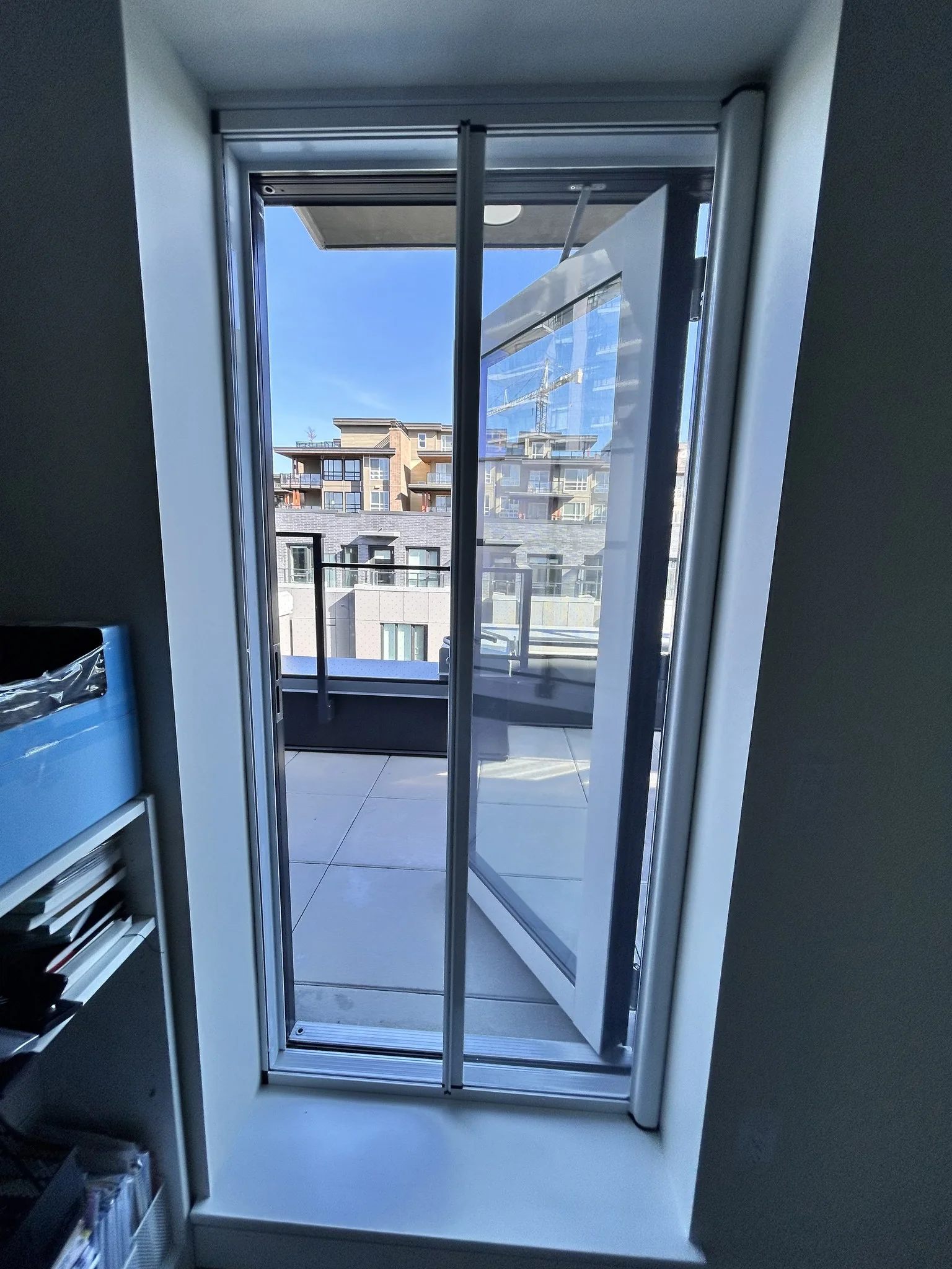 Retractable screen at an outward-opening balcony doorway